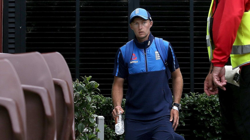 Joe Root, wearing his England tracksuit, walks past chairs at the SCG.