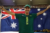 An Australian male pole vaulter stands holding the national flag behind him at the Budapest World Championships.