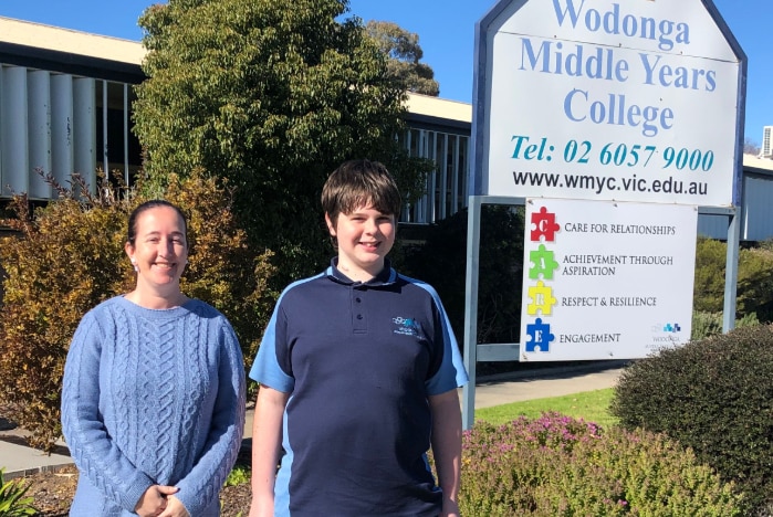 Sean Howison standing with his teacher Brook Darby in front of his school Wodonga Middle Years College on a sunny day.