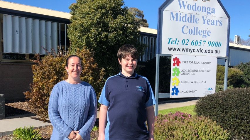 Sean Howison standing with his teacher Brook Darby in front of his school Wodonga Middle Years College on a sunny day.