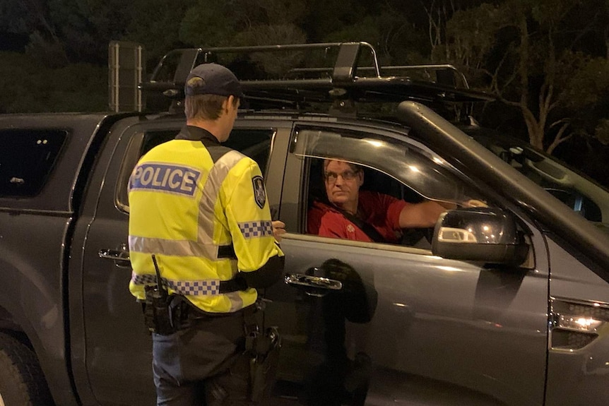 A policeman talking to a car driver in the darkness of early morning