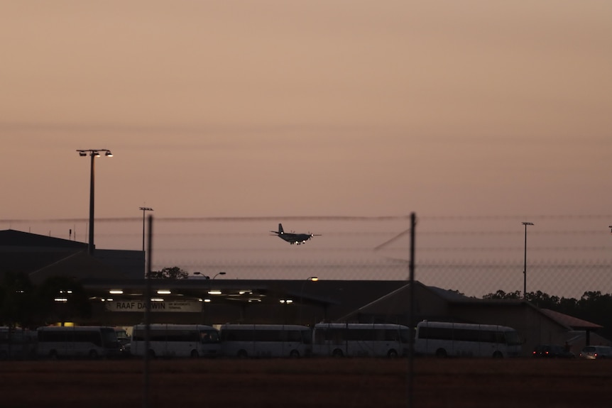 Plane flies into a runway at dusk with a sunset backdrop