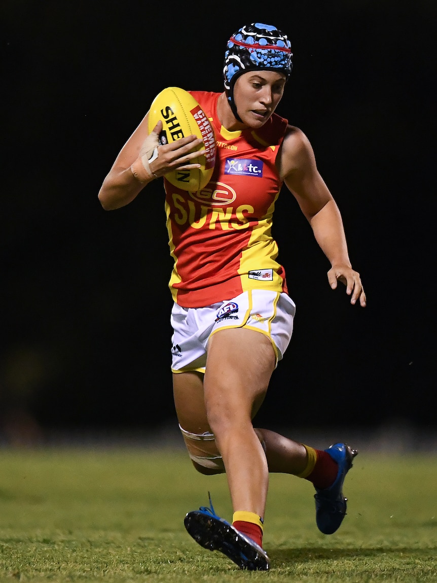 Tori Groves-Little memakai helm warna-warni saat melakukan latihan dengan bola di tangan