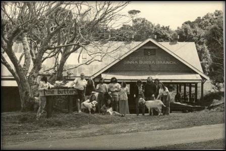 Black-and-white image of a residential rehab centre with residents and a couple of goats standing outside