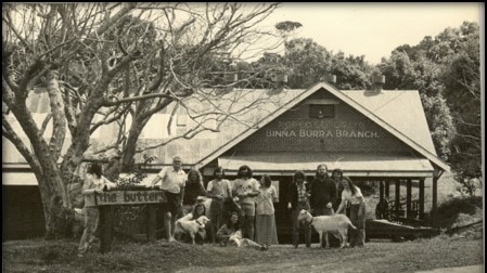 Black-and-white image of a residential rehab centre with residents and a couple of goats standing outside