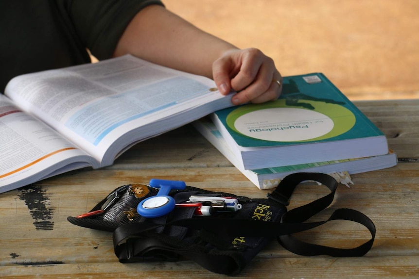 A person flicks through textbooks on a wooden table