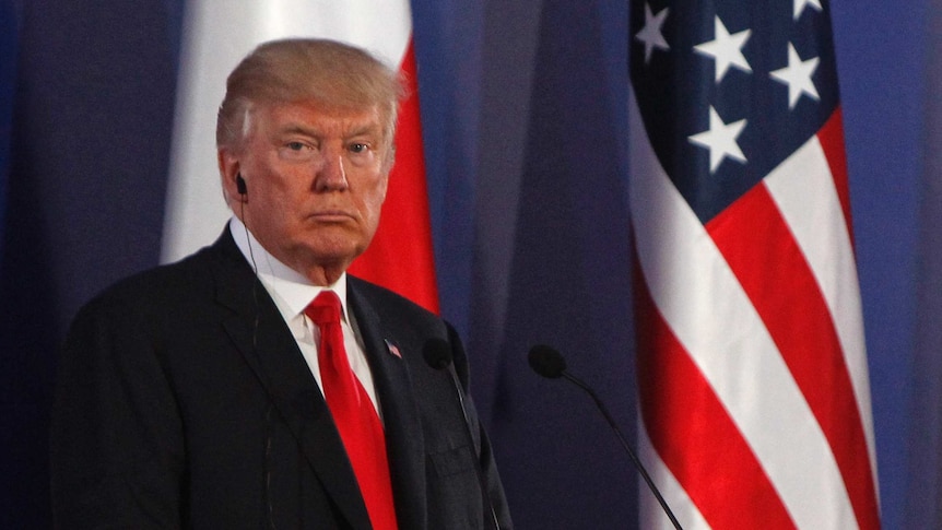 US President Donald Trump listens with an ear piece during a joint press conference in Poland.