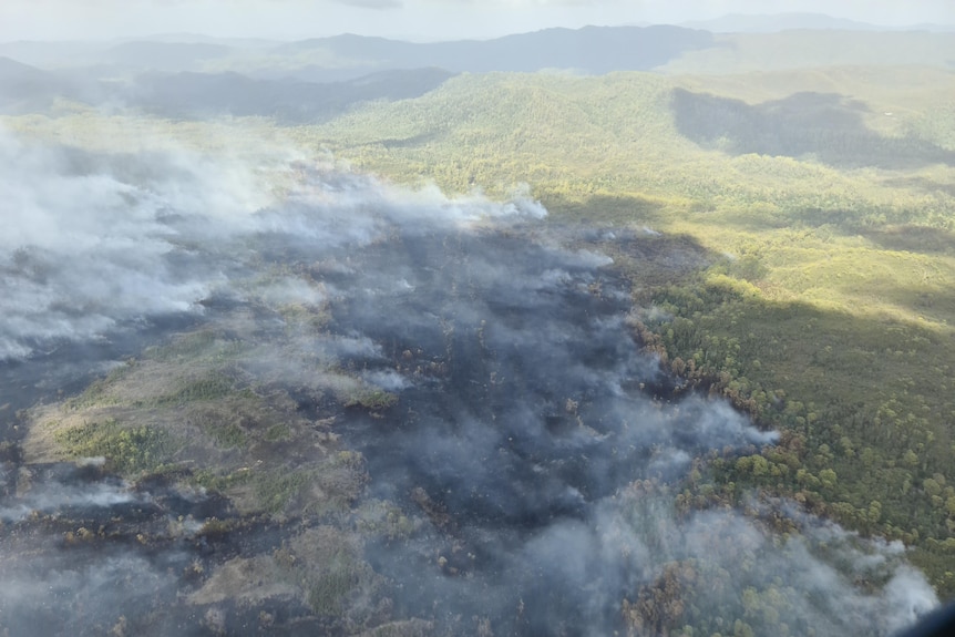 Aerial view of burned ground with smoke in the air 