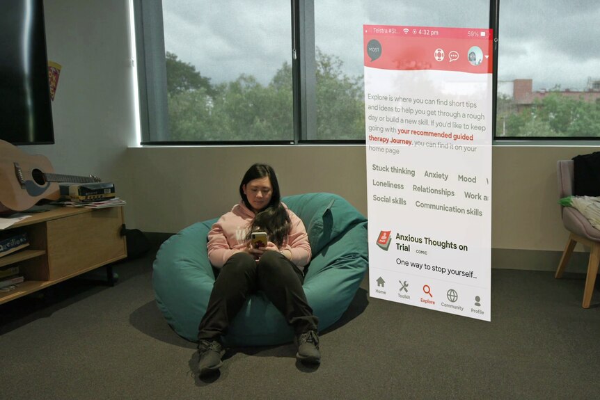 A young woman on a bean bag in a room looking at her phone.