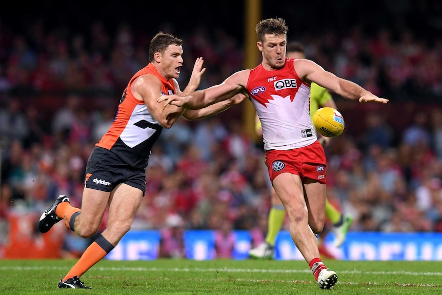 Heath Shaw moves in to tackle Luke Parker, who is about to kick the ball, during an AFL game.