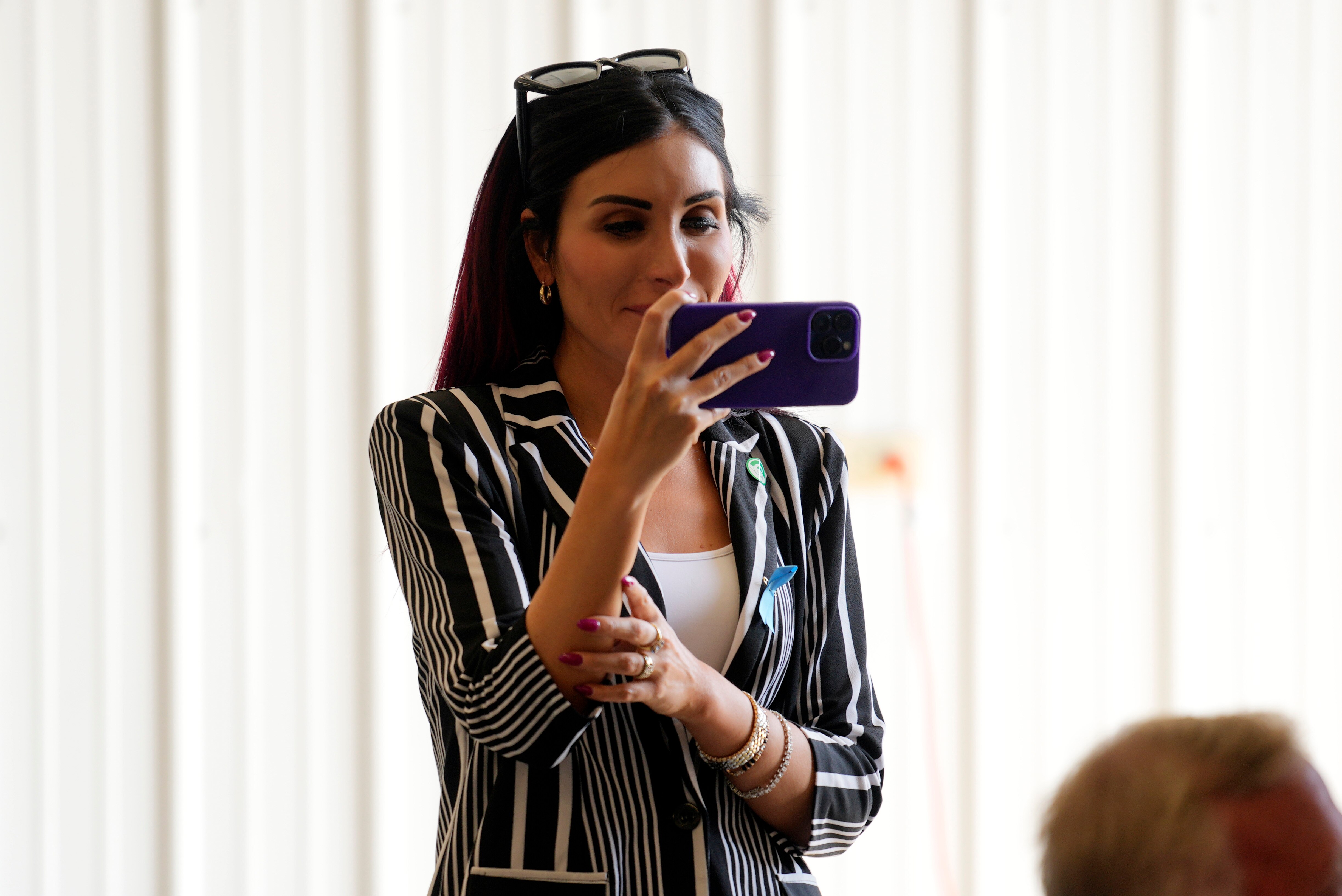 Laura Loomer holds her phone in front of her horizontally, apparently filming.