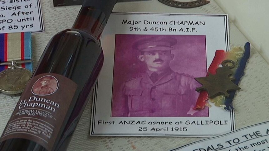 Photo of Major Duncan Chapman beside war medals and bottle of wine