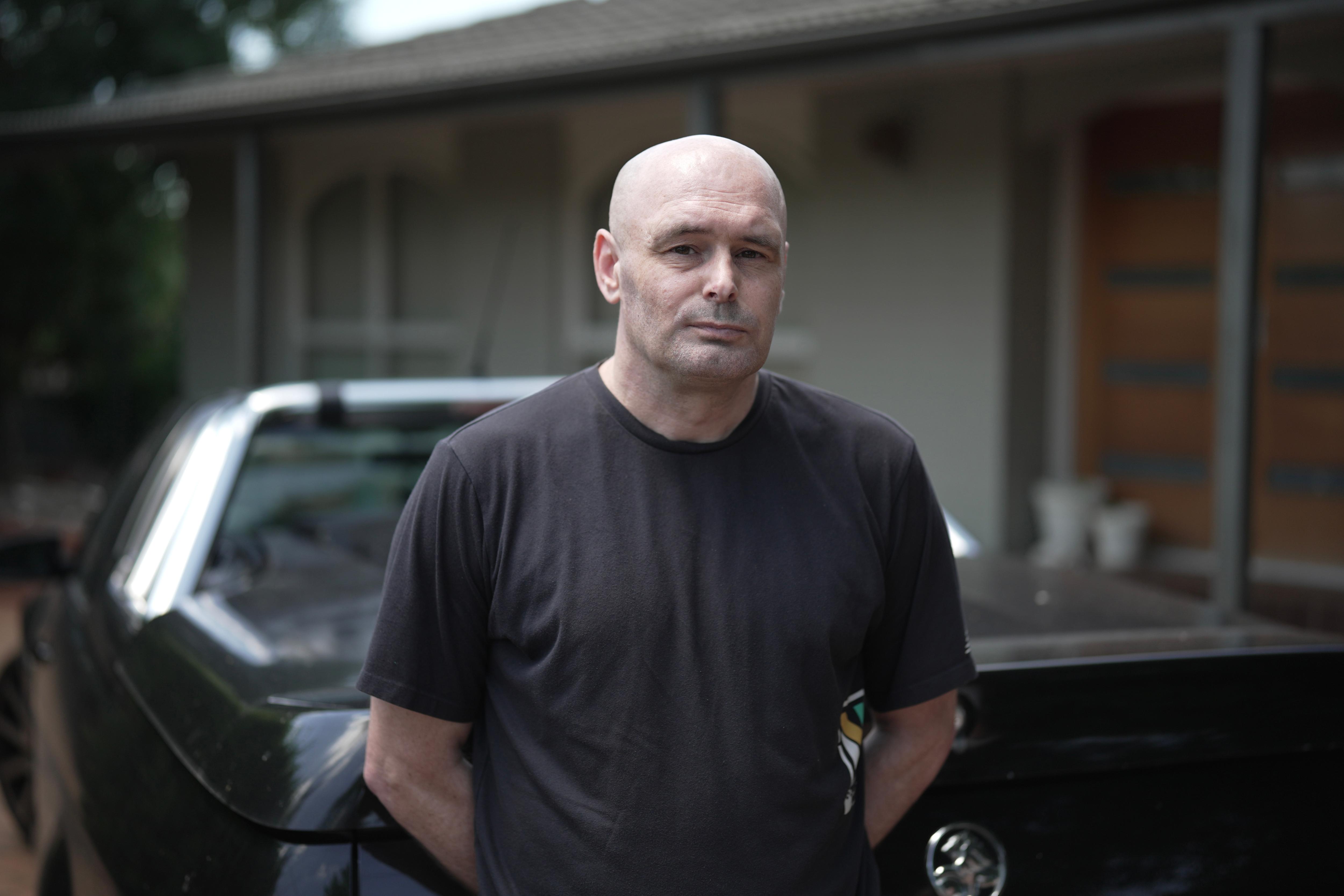 Jamie stands next to his car