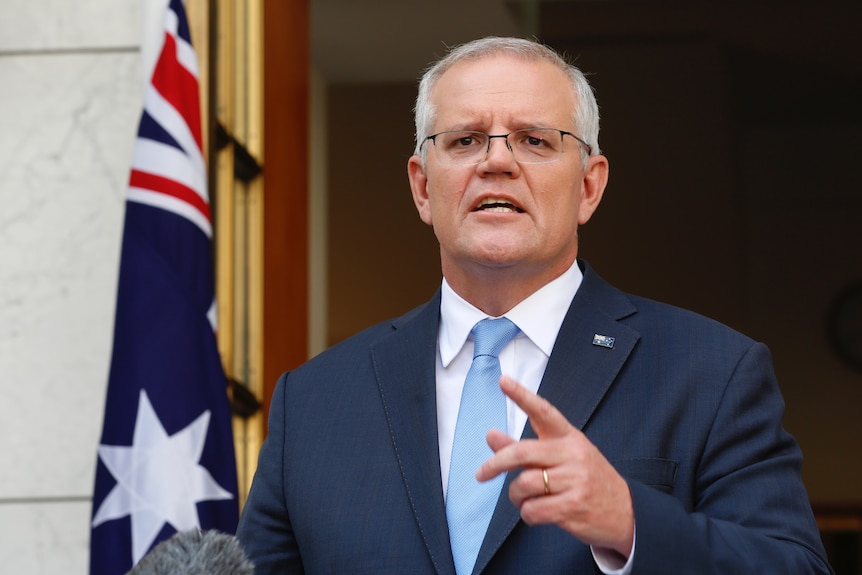 Scott Morrison wearing a light blue tie mid-sentence pointing with his left hand
