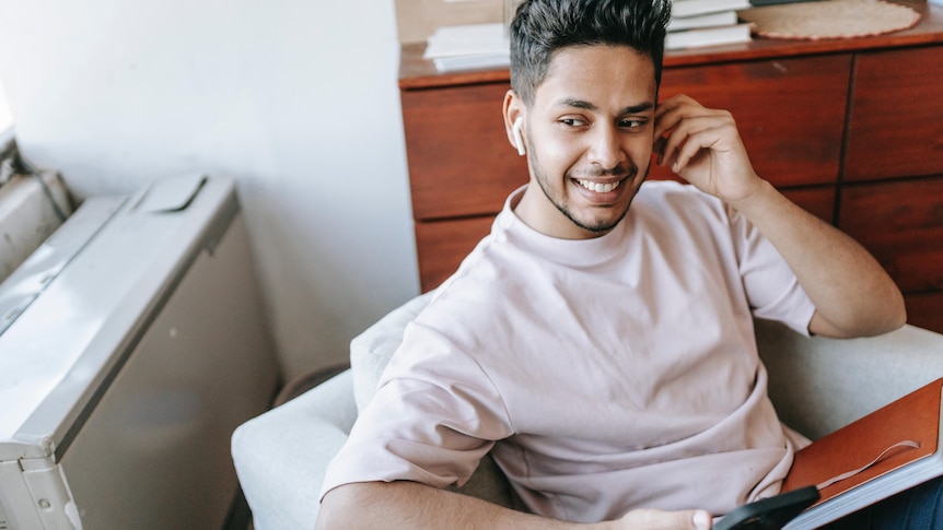 Man on the phone at home on the couch, trying to stay connected with friends during the pandemic. 