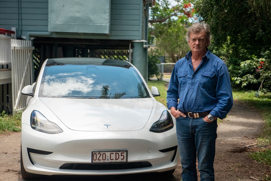 Grant Howard standing next to his Tesla in the driveway of his house in Mackay, November 2021.