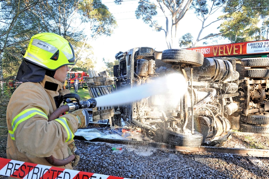 Emergency services hose down a truck after it collides with a tram in Parkville, Melbourne.