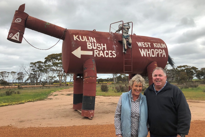 Large tin horse sculpture with male and female stood in foreground. Text on horse "Kulin Bush Races, West Kulin Whoppa"