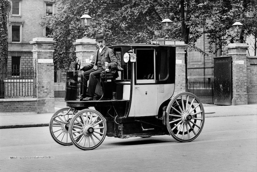 a 19th century man sits upon a carriage with a steering consul