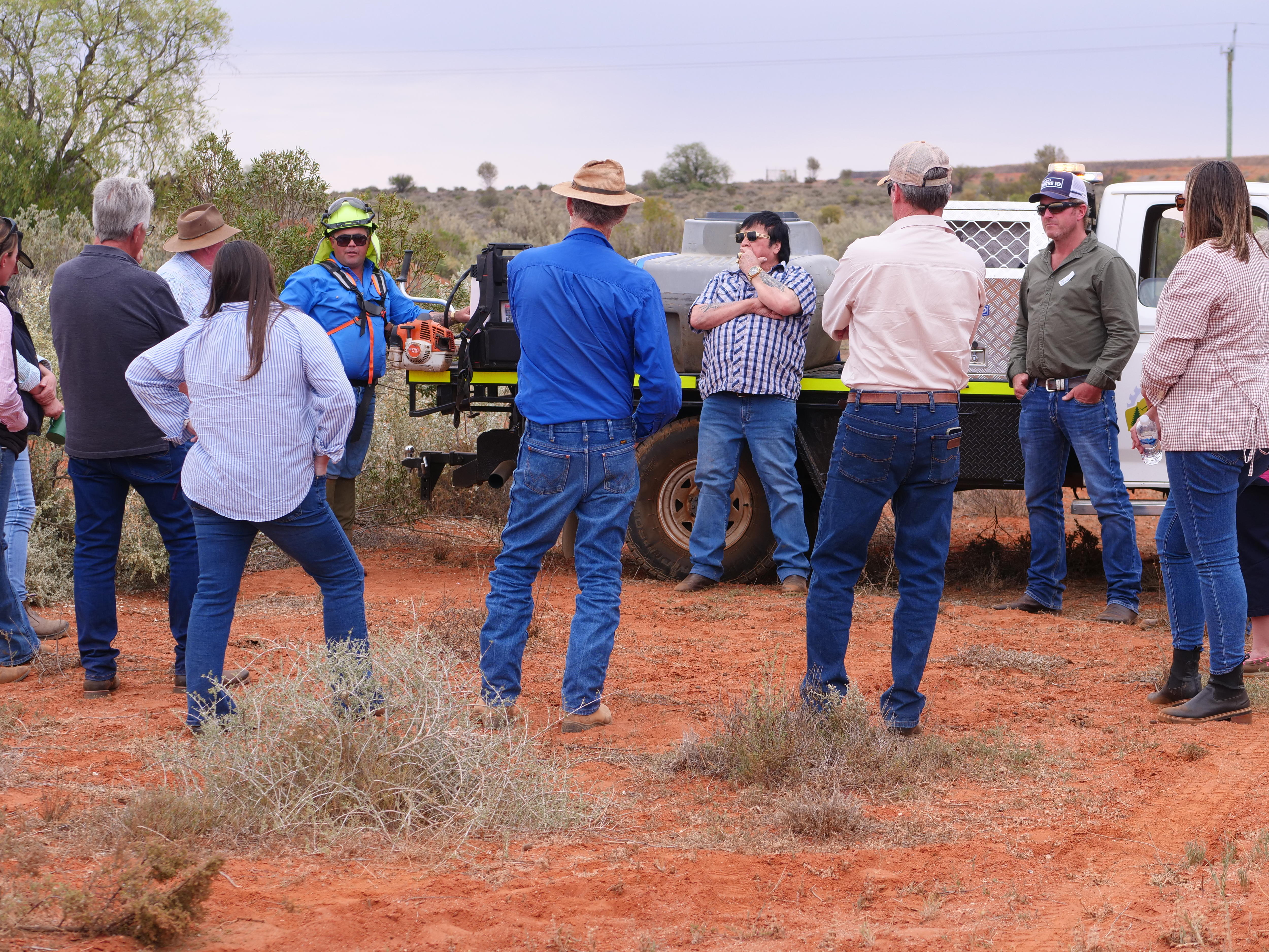 um grupo de pessoas forma um círculo na área interna com um homem liderando contra um caminhão