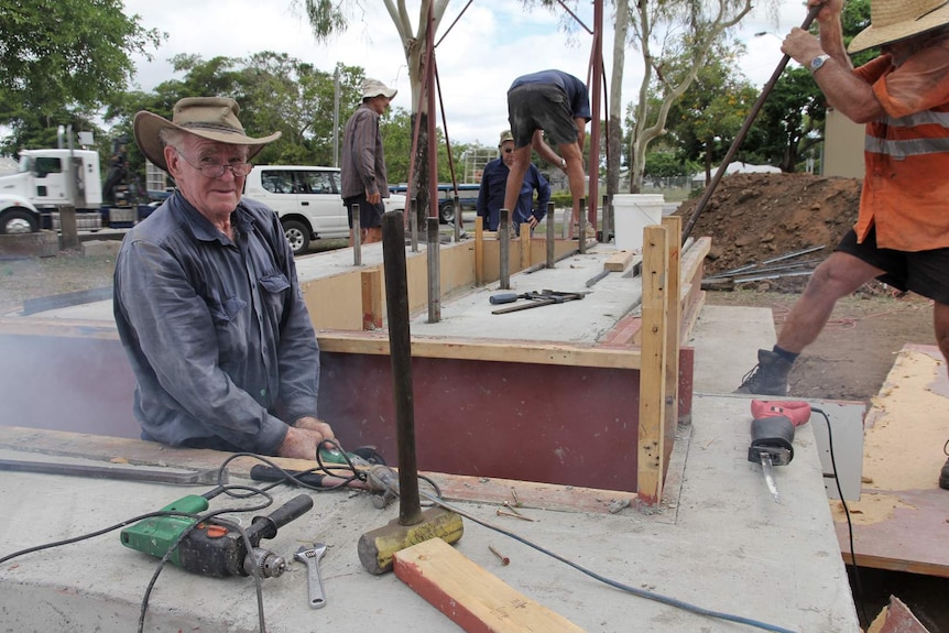 Men with power tools work on a concrete block