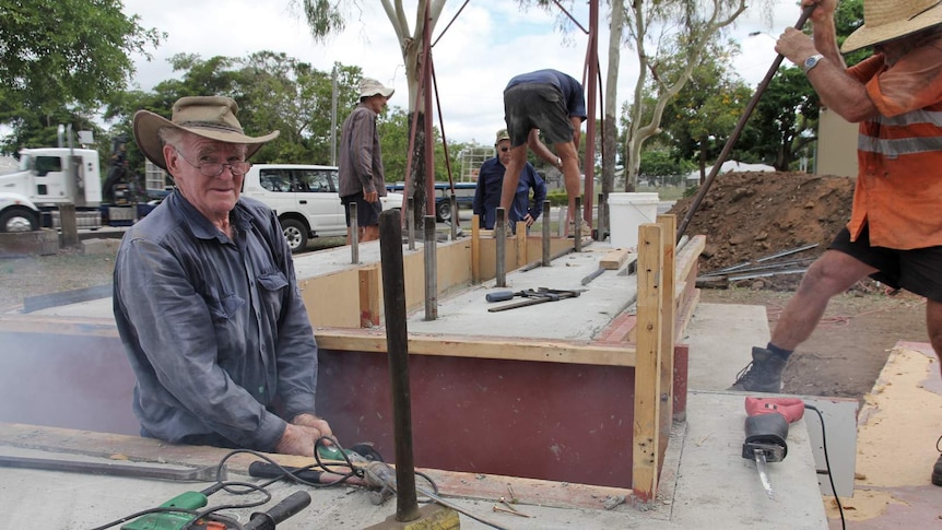 Men with power tools work on a concrete block