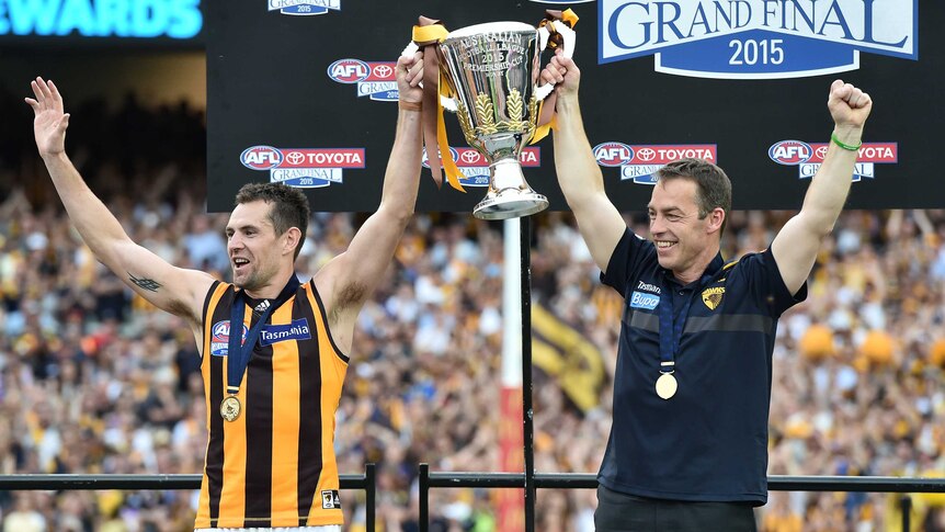 Luke Hodge and Alastair Clarkson lift the AFL premiership trophy in 2015.