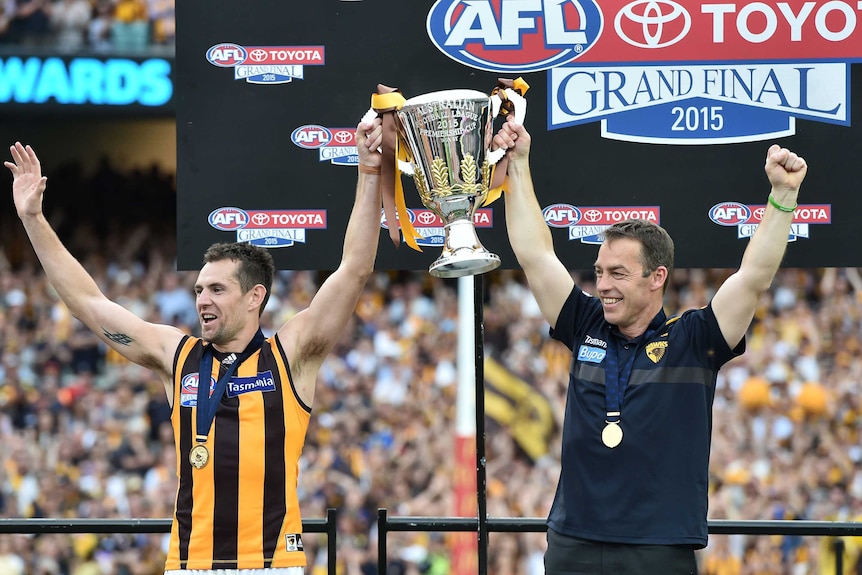 Luke Hodge and Alastair Clarkson lift the AFL premiership trophy in 2015.