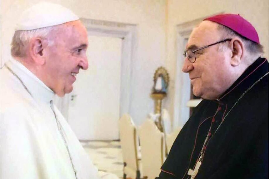 A man in pope's dress face to face with a man dressed as a bishop