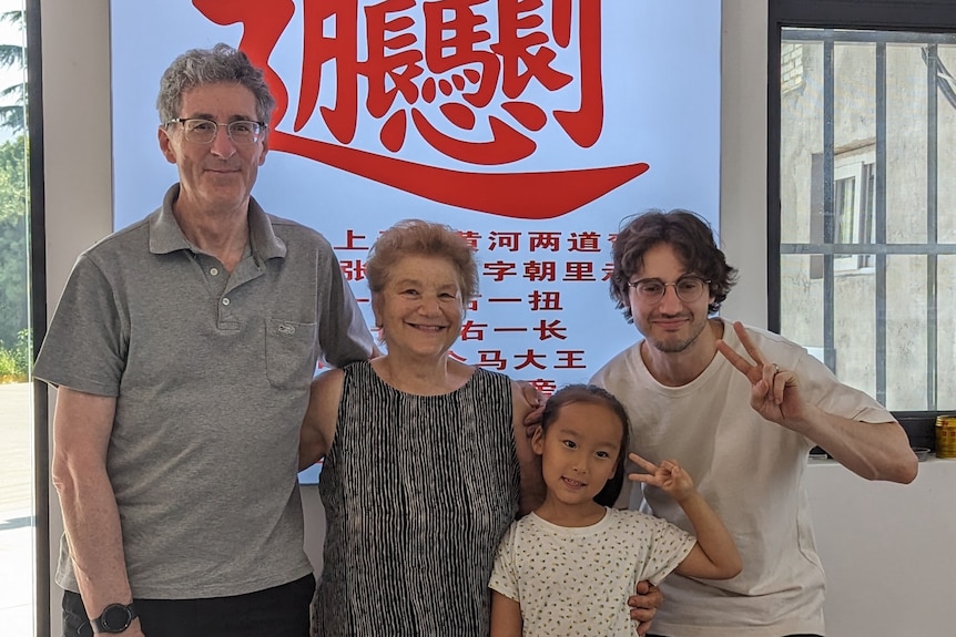 Four people standing in front of a shop sign in Chinese