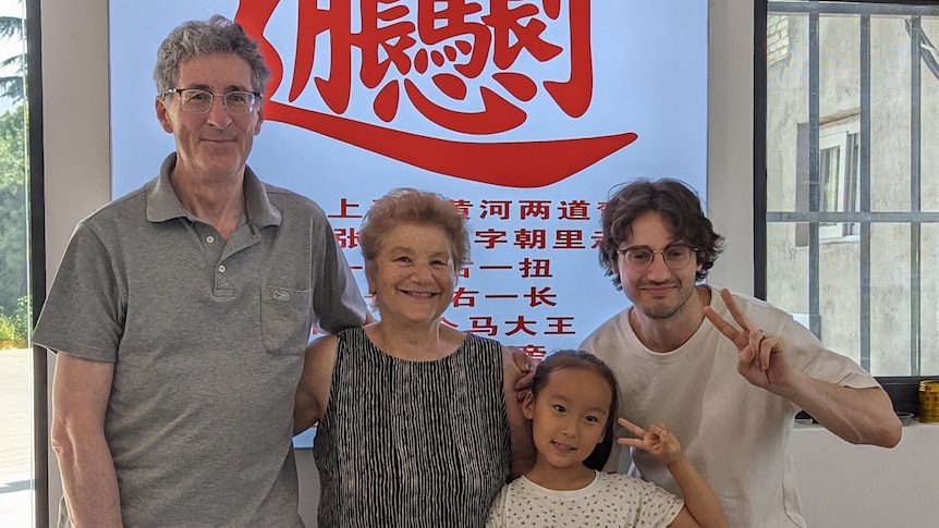 Four people standing in front of a shop sign in Chinese