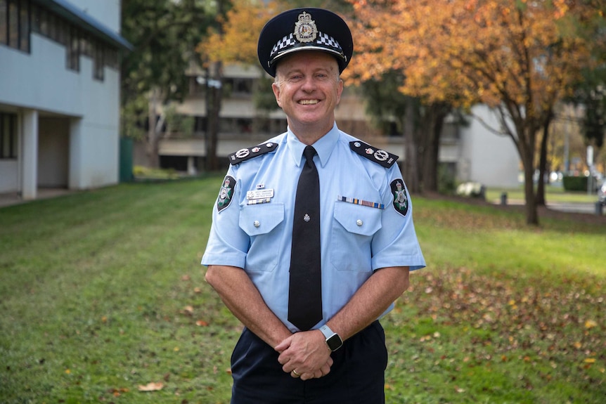 A friendly-looking man in a police officer's uniform smiles at the camera