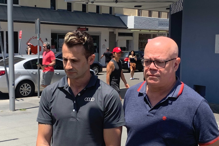 Two men outside, one bald with glasses, the other in an audi shirt