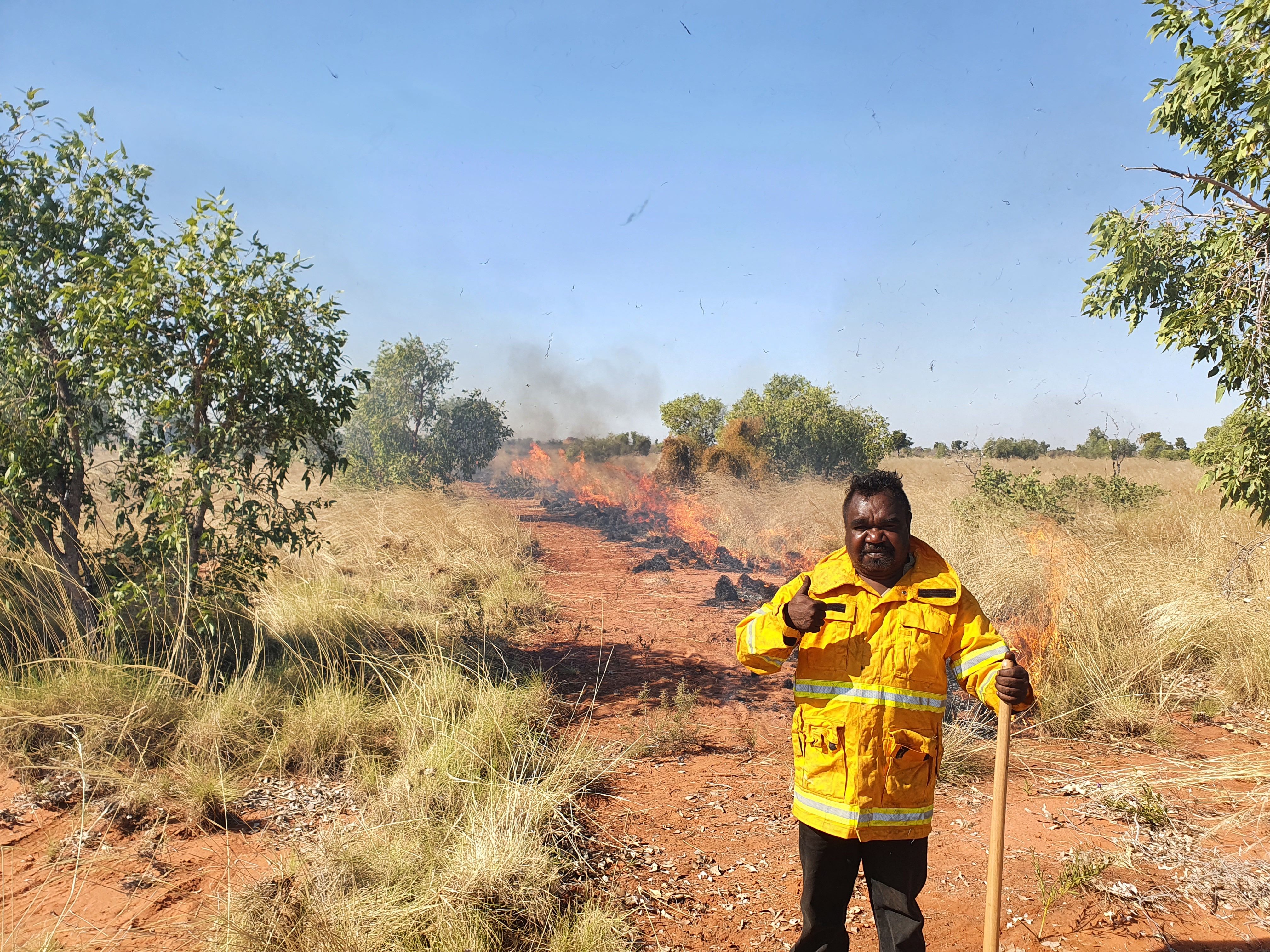 Ein Mann steht vor brennendem Gras.