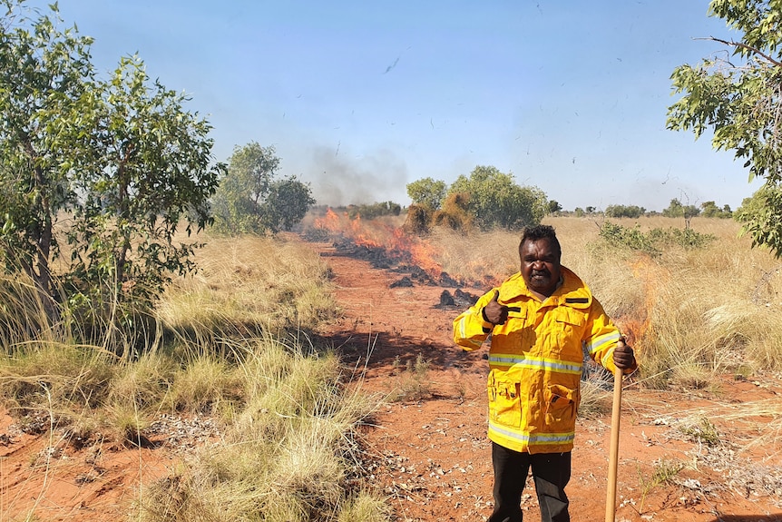 A man standing in front of burning grass.