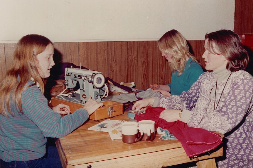 Three women sewing at a table.