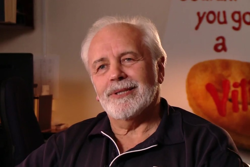 A man with a white beard and hair wearing a blue shirt