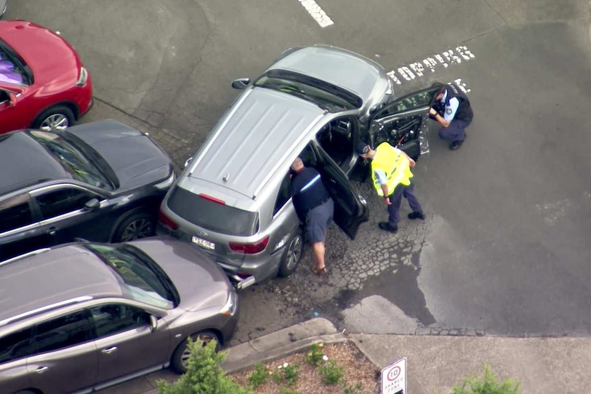 police inspecting the inside of a vehicle in a parking lot