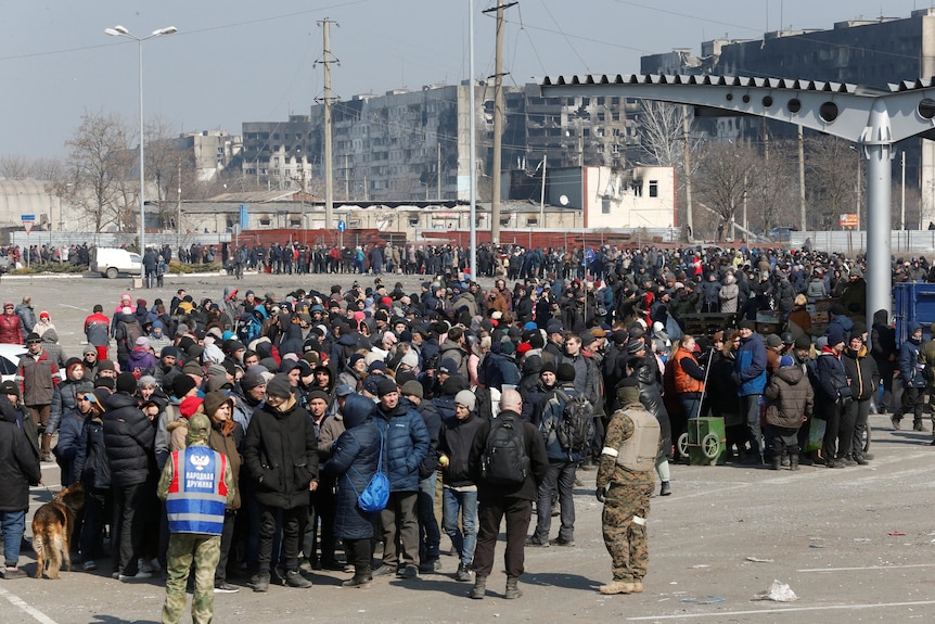 People stand in a long queue for aid.