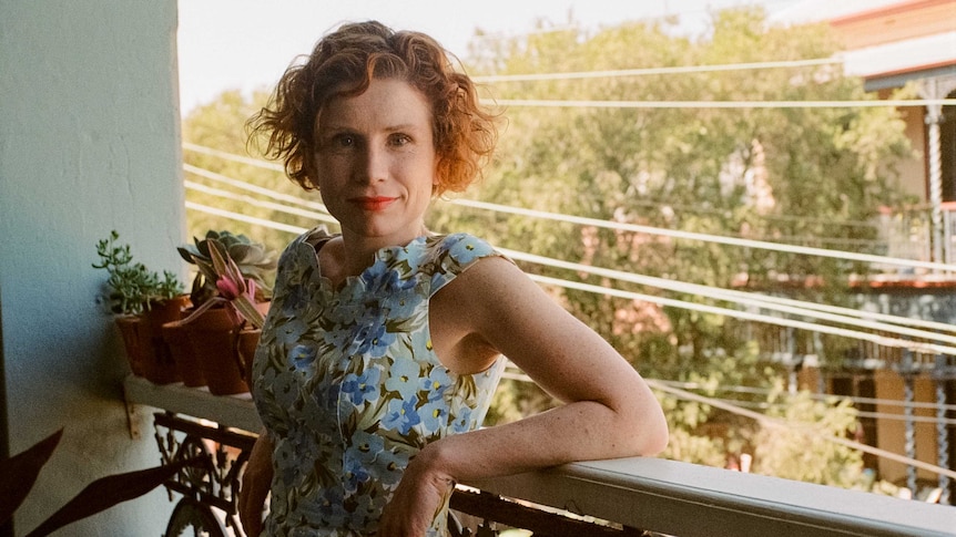 Fiona Wright stands on a balcony with plants in story about working from home due to coronavirus and looking after mental health