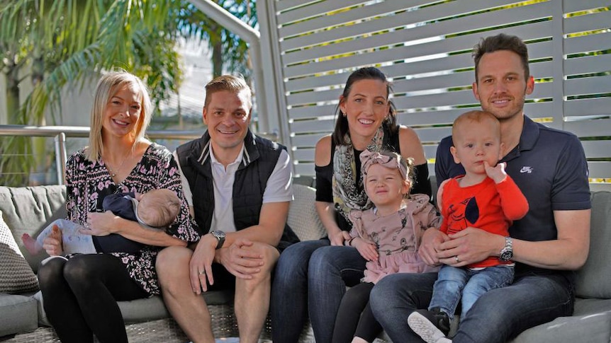 two couples sit down outside with their children