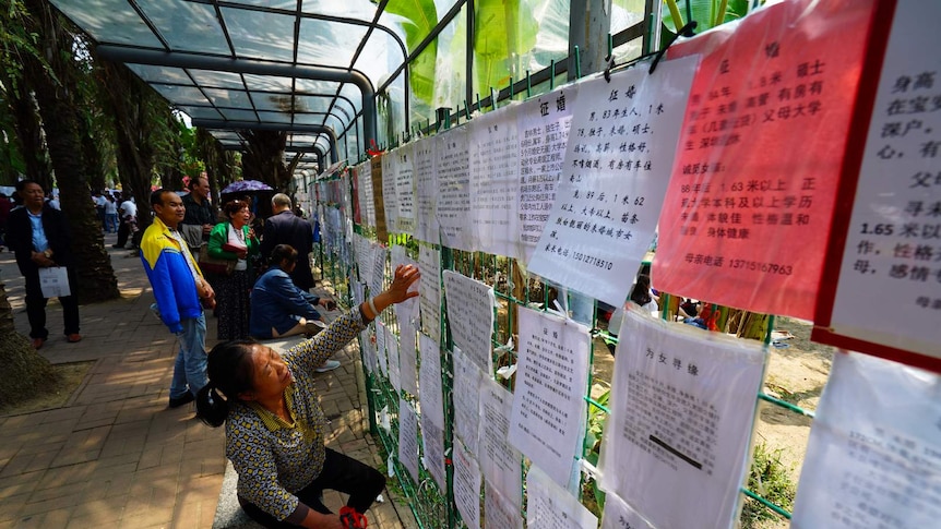 A woman points as she reads one of the personal advertisements.