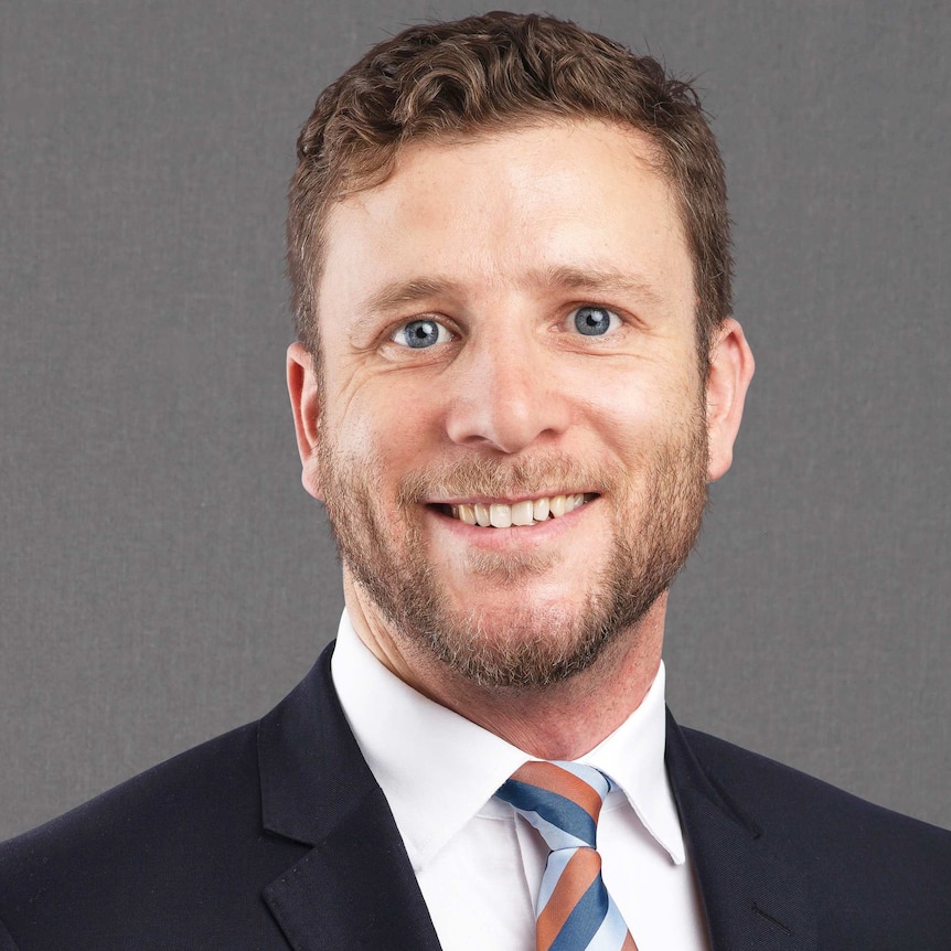 Head shot of a smiling Josh Mennen against a grey background.