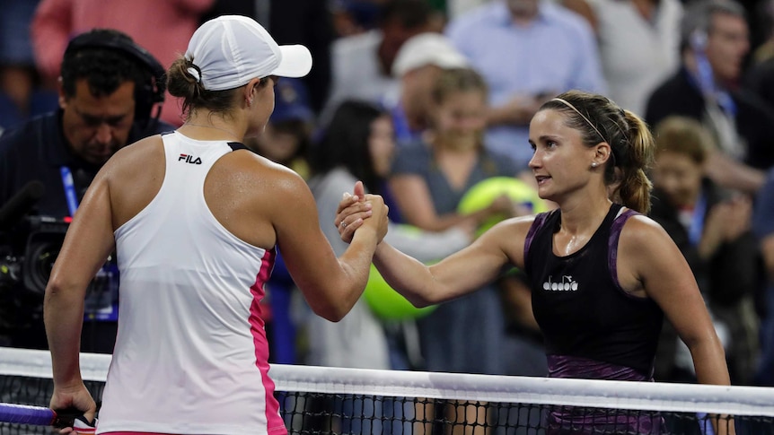 Two female tennis players shake hands at the net after their singles match at the US Open.