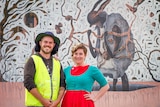 Image of two people posing in front of a mural in Kalgoorlie, Western Australia.