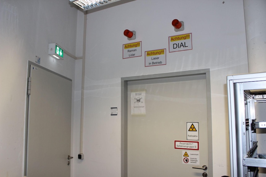 A door to a laboratory with warning signs and red lights around the door frame