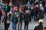 Pedestrians cross Flinders Street near Swanston Street in Melbourne's CBD