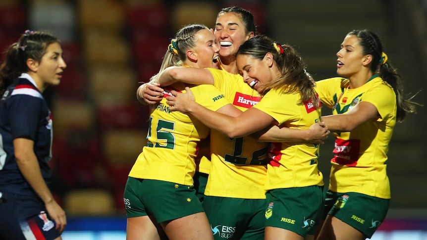 Jillaroos players hug after another try against France at the Women's Rugby League World Cup.