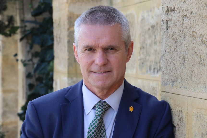 Liberal MP David Blayney leans against a wall.