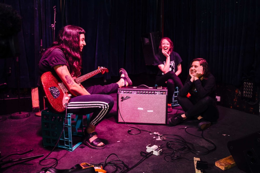 Camp Cope members relaxing on stage.
